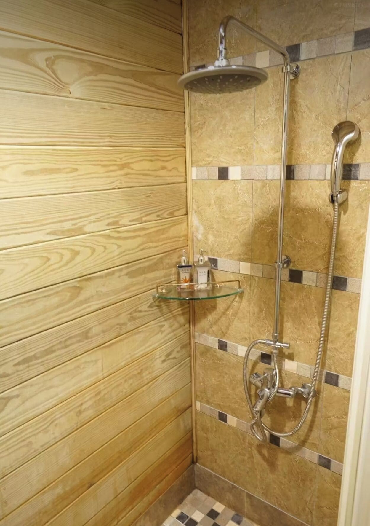 Zona de ducha con repisa de vidrio, cabezal de ducha de mano y cabezal de ducha empotrado.