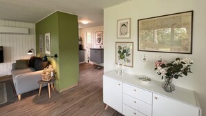 Un salon avec un mur d’accent vert, un canapé blanc, une petite table d’appoint et un meuble blanc agrémenté d’objets décoratifs.