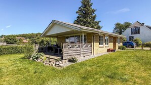 Une maison de plain-pied dotée d’un patio couvert, de fondations en pierre et d’un petit jardin.