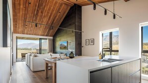 Een moderne keuken met een groot eiland, houten plafond en grote ramen met uitzicht op de bergen.