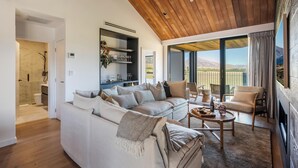 Een moderne woonkamer met een houten plafond, een witte bank, een bijzettafeltje en uitzicht op de omgeving.