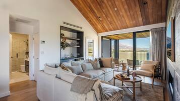 A modern living room with a wooden ceiling, a white sofa, a coffee table, and a view of the outdoors.