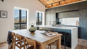 Een moderne keuken met een centraal eiland, een houten eettafel en stoelen.