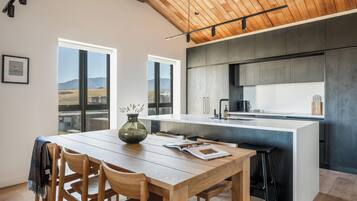 A modern kitchen with a central island, wooden dining table, and chairs.