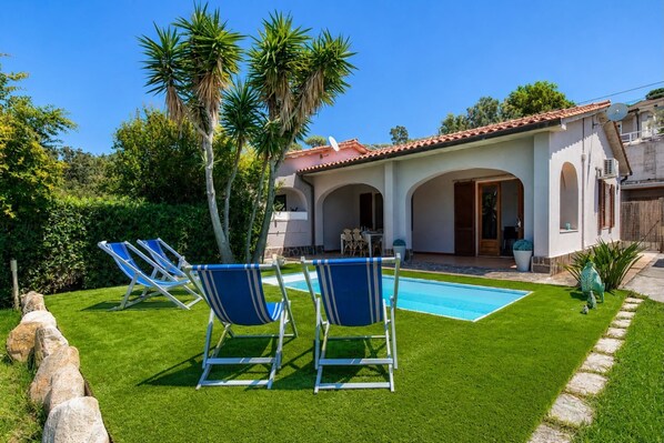Ein Poolbereich mit Liegestühlen, einem Pool und einem Gebäude mit Bögen und einem Ziegeldach.