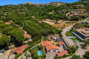 Eine Vogelperspektive eines Wohngebiets mit Häusern, einem Swimmingpool und einer hügeligen Landschaft im Hintergrund.