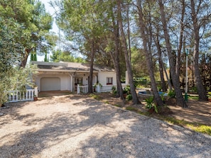 A house with a covered porch, a garage, and a gravel driveway surrounded by trees. - Private pool house, barbecue and petanque (L'Ametlla de Mar)