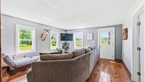 Ein Wohnzimmer mit Ecksofa, einem aufgehängten Hirschgeweih und einem Fernseher.