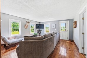 A living room with a sectional sofa, a mounted deer head, and a TV. - Walnut Grove- fenced yard- rural getaway (Coloma)