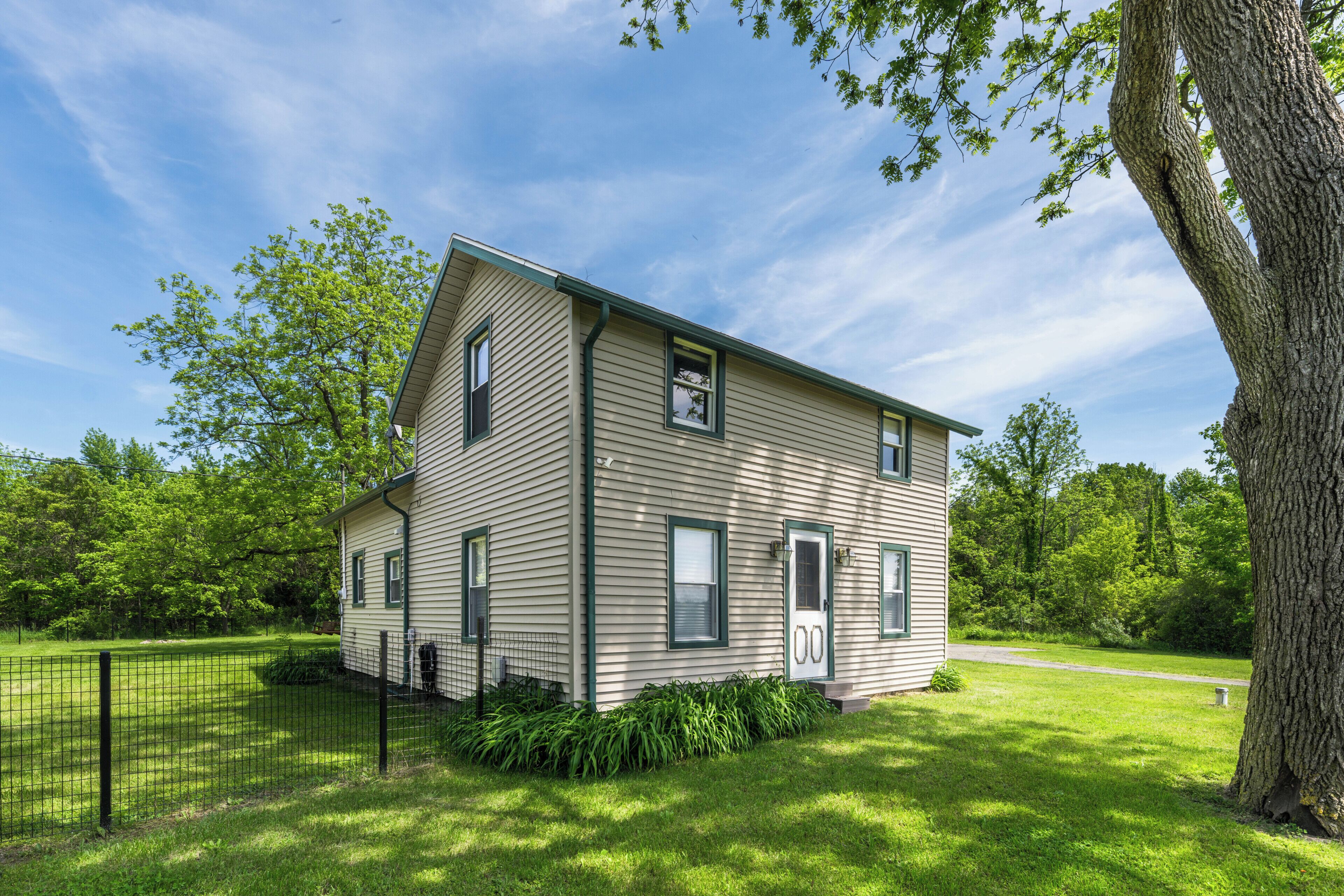 A two-story house with a sloped roof, a front porch, and a fenced yard.