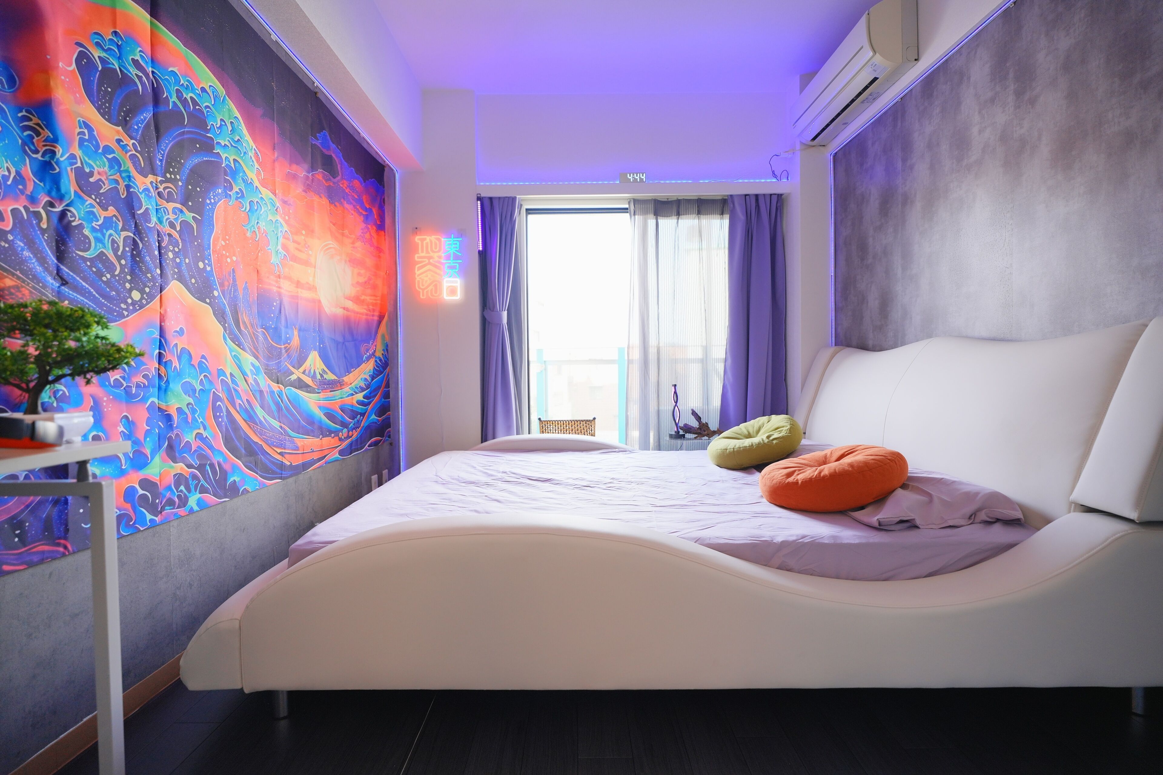 Une chambre moderne avec un grand lit, une tapisserie aux couleurs vives et une vue sur l’extérieur.