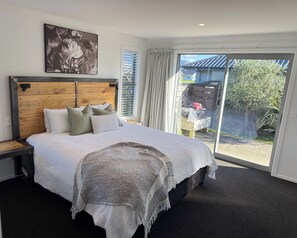 A bedroom with a large bed, a wooden headboard, a view of the outside, and a framed picture on the wall.