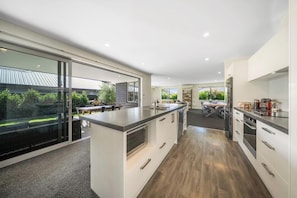 A modern kitchen with a large island, built-in appliances, and a view of the outdoors.