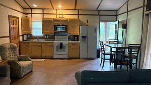 A compact kitchen with wooden cabinets, a microwave, oven, and refrigerator. There is a dining area with a table and chairs. - Shawnee Pines #2 - Studio (Golconda)