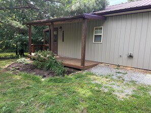 A single-story building with a wooden deck, a small window, and a door.