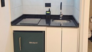 Ett kompakt kök med mikrovågsugn, diskho och ett litet skåp märkt med texten ”Whirlpool”.