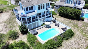 Ein mehrstöckiges Haus mit Swimmingpool, einer überdachten Terrasse und Blick auf die umliegende Nachbarschaft.