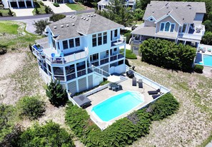 Ein mehrstöckiges Haus mit Swimmingpool, einer überdachten Terrasse und Blick auf die umliegende Nachbarschaft.