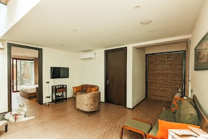 A modern living room with a sofa, a television, and a wooden floor.