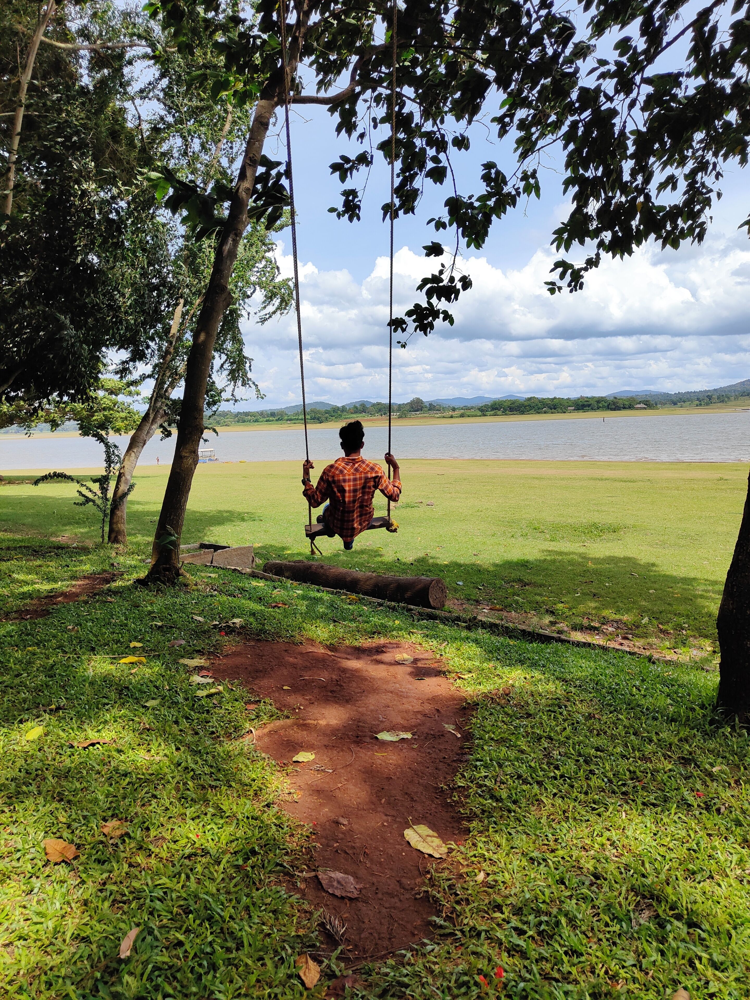 A swing set in a park with a lake and hills in the background.