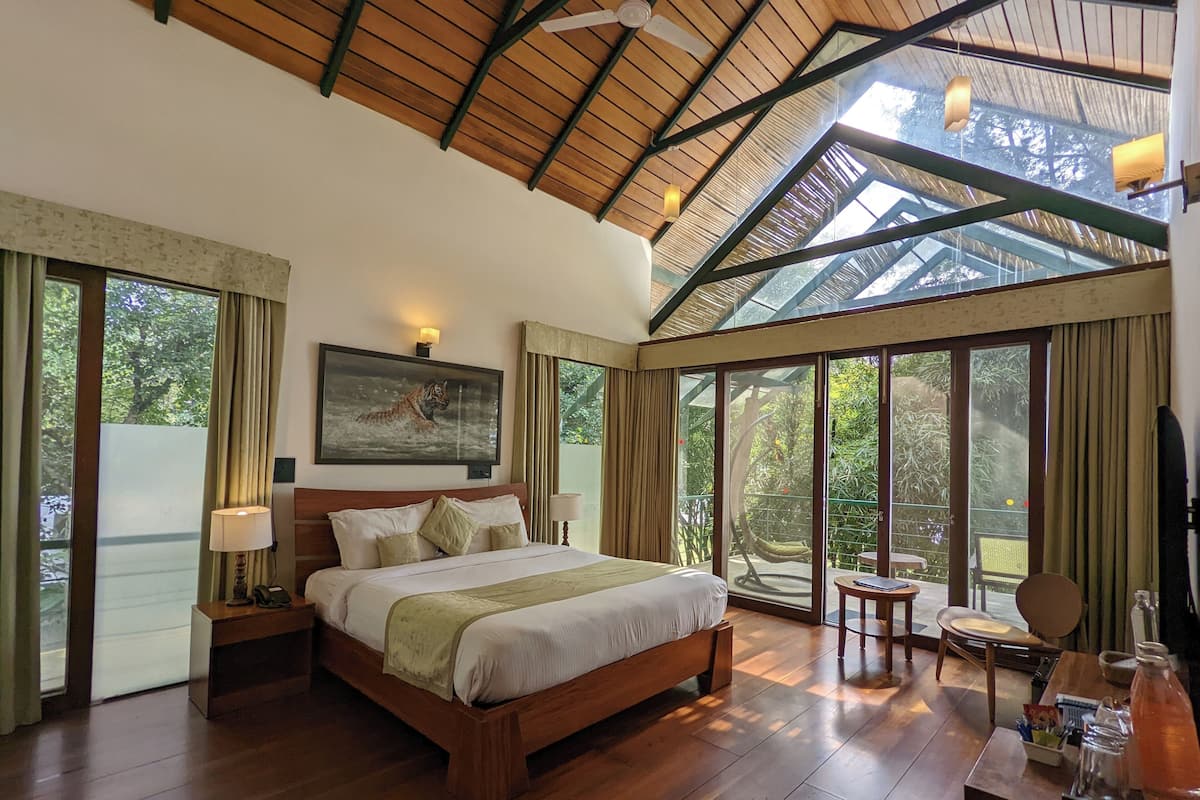 A spacious bedroom with a large bed, a ceiling fan, and a view of the outdoors through large windows.