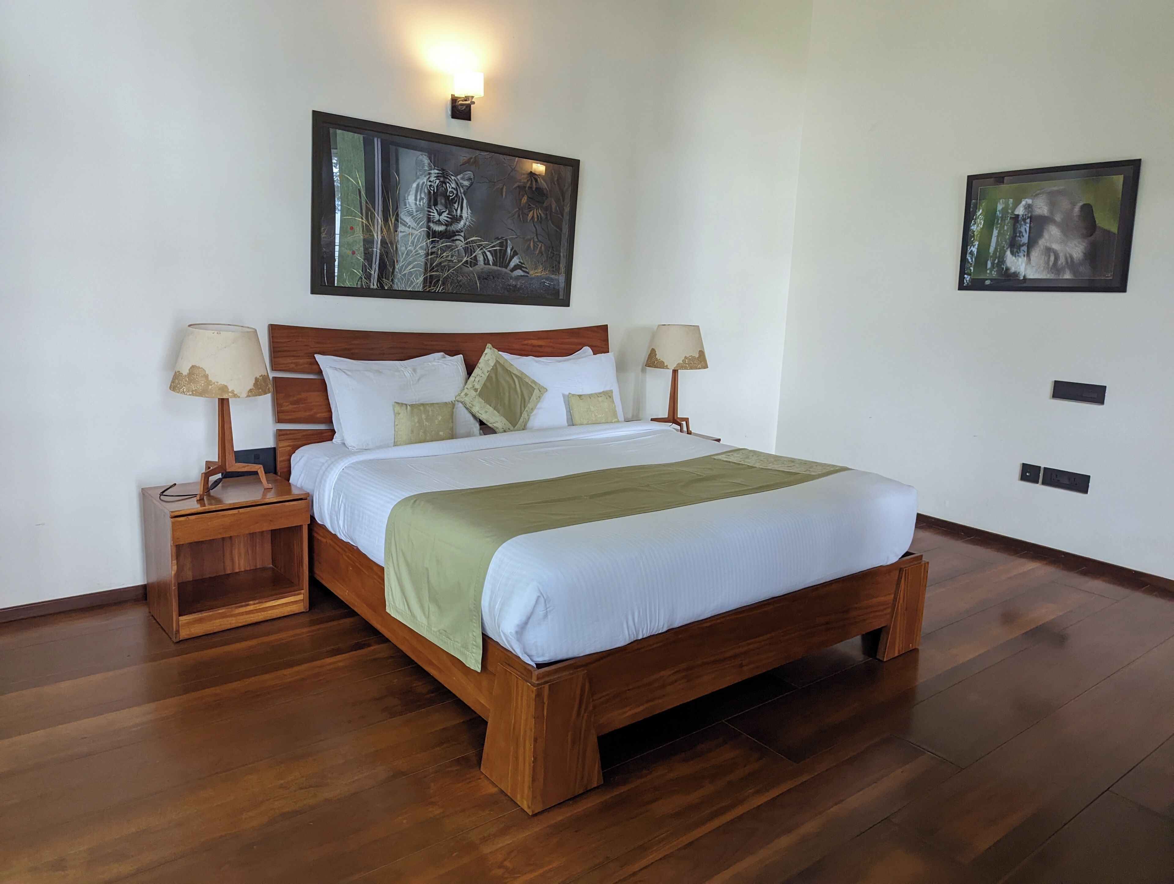 A neatly made bed with a wooden frame, two bedside tables with lamps, and two wall-mounted light fixtures.