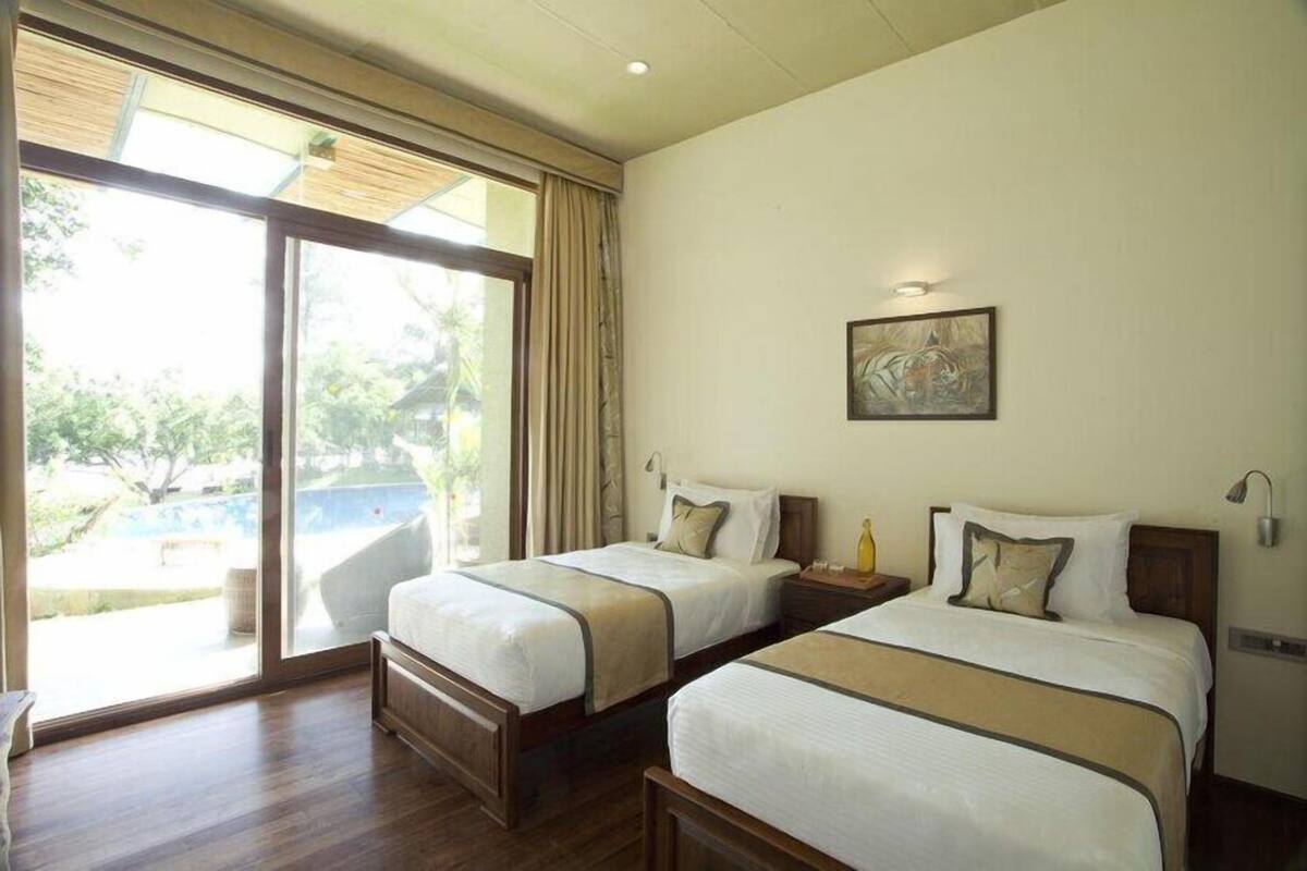 A hotel room with two beds, a large sliding glass door to the outside, and a painting on the wall.