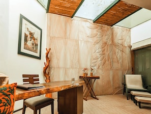 Un interior moderno con una mesa de madera, sillas, un cuadro enmarcado y un detalle decorativo en la pared.