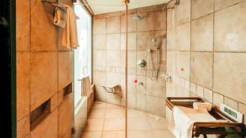 Un baño con ducha, lavamanos y un perchero para toallas.