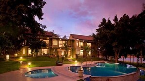 A two-story building with a swimming pool, surrounded by trees and a well-lit patio area. - Waterwoods Lodge Kabini (Heggadadevankote)
