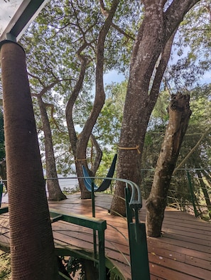 A wooden deck with a hammock, surrounded by large trees. - Waterwoods Lodge Kabini (Heggadadevankote)