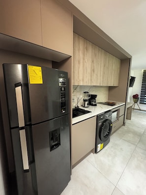 A modern kitchen with a refrigerator, washing machine, and a coffee maker. - La Carolina Studio (Quito)