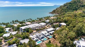 Una zona residenziale sulla costa, con case moderne, una piscina e vista sull'oceano.