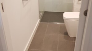 Ein schmales Entree mit Toilette und Fliesenboden.