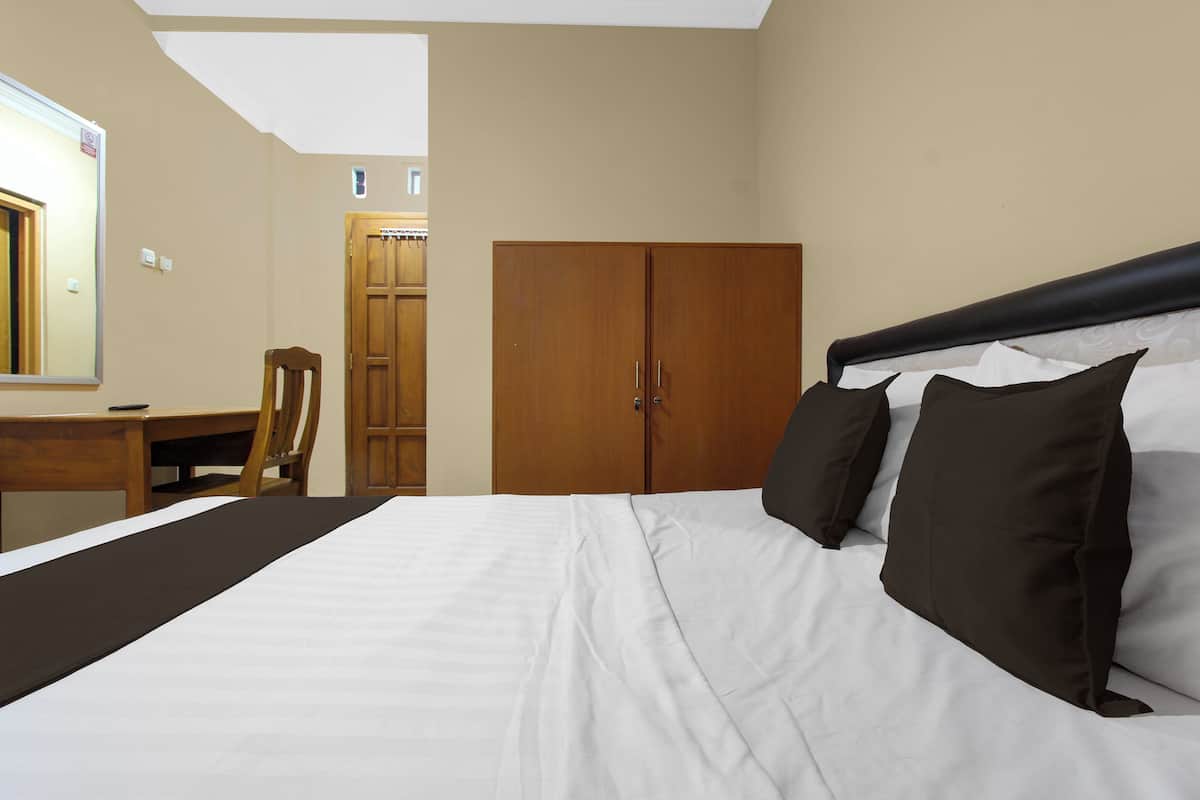 Quarto com cama, guarda-roupa de madeira, escrivaninha com cadeira e espelho.