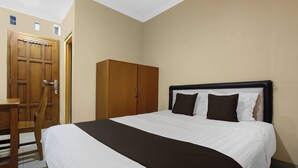 Een slaapkamer met een bed, een houten kledingkast en een bureau.