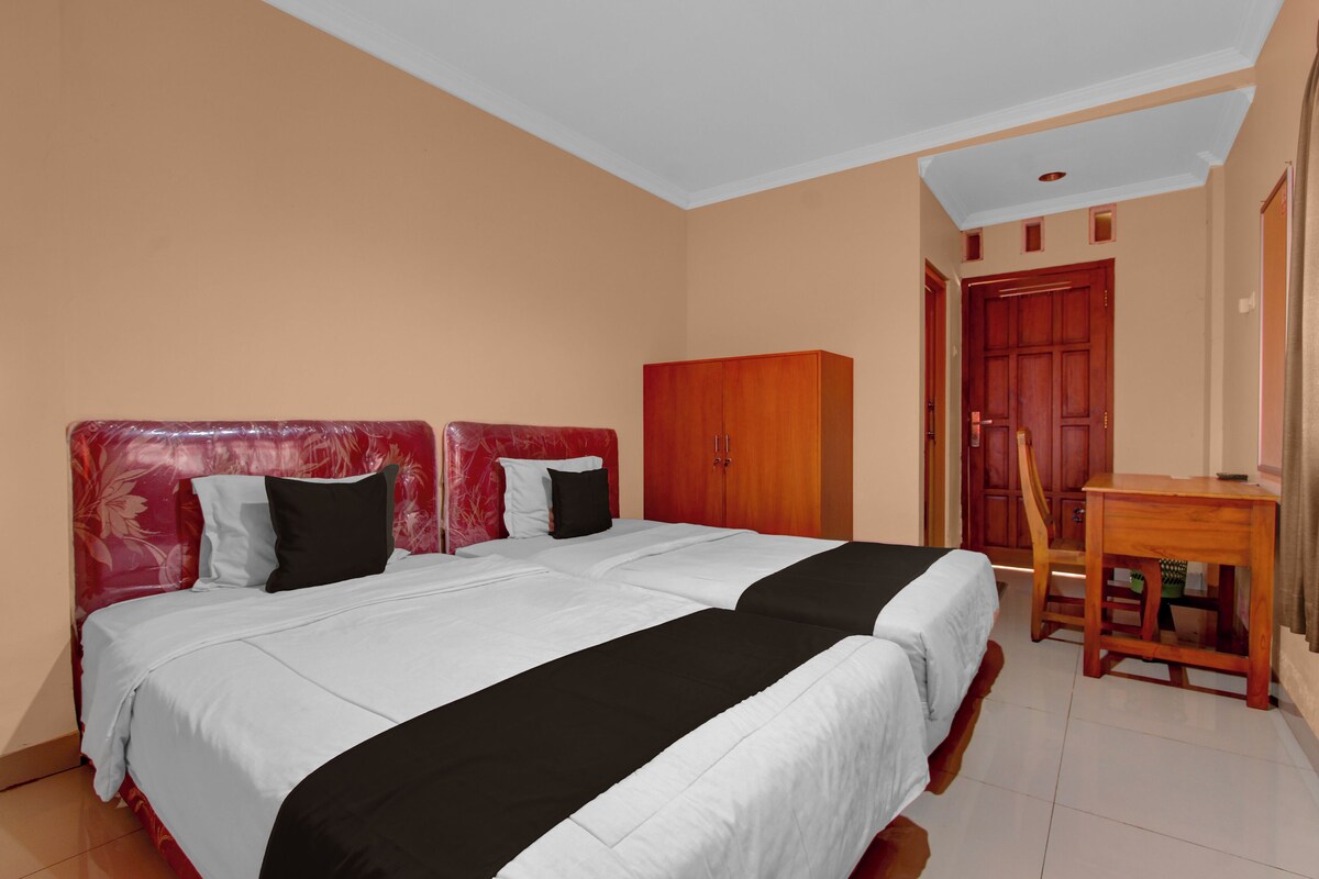 A bedroom with a double bed, a wooden wardrobe, and a desk with a chair.