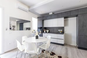 Una cucina moderna con mobili bianchi, un tavolo rotondo con sedie bianche e un'isola centrale.