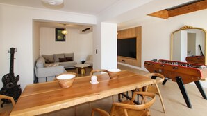 En matplats med ett träbord och stolar, en soffa, en tv och ett bordtennisspel.