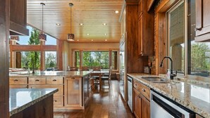A spacious kitchen with wooden cabinetry, granite countertops, and a large island. - Spring Shores Lodge | Luxury Mtn Estate, Sleeps 40, Private Lake & More! (Ashton)