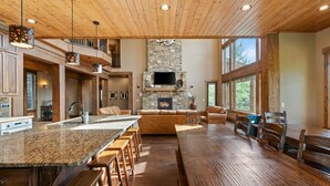 A spacious kitchen with a large island, stone fireplace, and wooden ceiling. - Spring Shores Lodge | Luxury Mtn Estate, Sleeps 40, Private Lake & More! (Ashton)