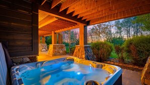 A hot tub area with stone pillars and a view of trees. - Spring Shores Lodge | Luxury Mtn Estate, Sleeps 40, Private Lake & More! (Ashton)