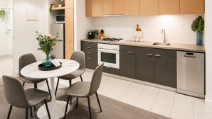 Una cocina moderna con comedor, que incluye una mesa redonda con sillas, horno empotrado y lavavajillas.