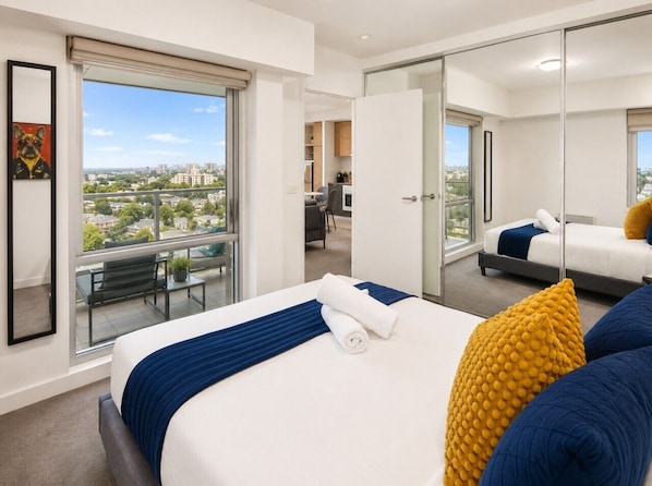 Ein Hotelzimmer mit einem großen Bett, einem Balkon mit Blick, einem separaten Essbereich und einem Spiegelkleiderschrank.