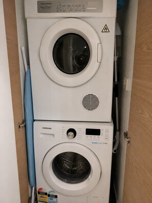 Ein übereinander angeordneter Wasch- und Trockner, mit Bedienfeldern und Sicherheitshinweisen.