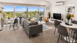 Una sala de estar moderna con sofá, sillas, mesa de comedor y televisor.