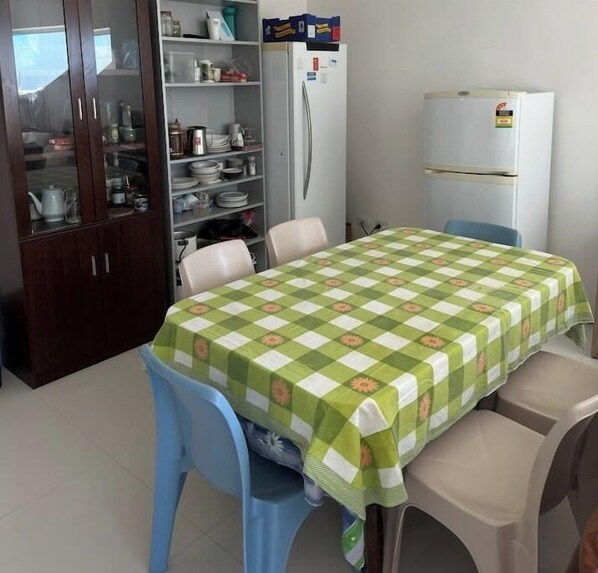 A dining area with a table covered by a green and white checkered tablecloth, surrounded by blue chairs.