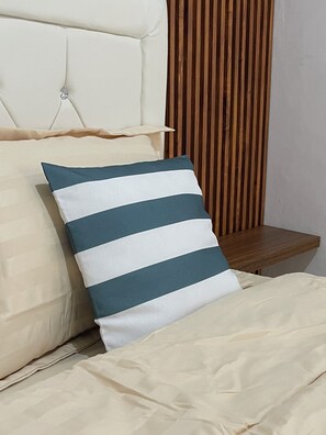 A bed with a striped pillow, a tufted headboard, and a wooden panel wall. - Saren Muding, a hidden corner of 2-bedroom house with AC in charming Kerobokan (Badung)
