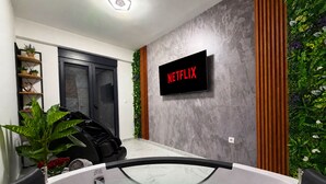 Ett modernt badrum med badkar, dusch och en väggmonterad tv som visar ”NETFLIX”.