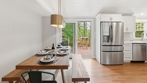 Una cocina moderna con electrodomésticos de acero inoxidable, una mesa de comedor de madera y un banco.